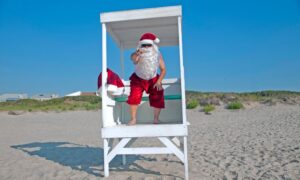 Man dressed up as Santa sitting in a lifeguard ladder on the beach