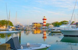 A view of Harbour Town on Hilton Head Island with boats docked and the iconic red and white striped lighthouse in the distance